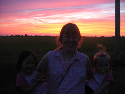 Mommy holds her babies in front of a pretty sunset